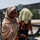 A mother holds her child, covered with a towel to avoid sunlight, on May 21.